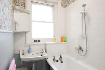 A bathtub with shower above on the first floor is near all the bedrooms.