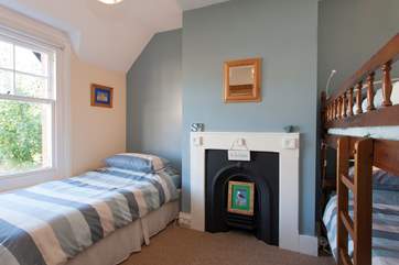 This family bedroom has a set of bunks and a day bed, along with a pretty Victorian feature fireplace