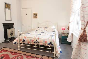 The light and comfortable master bedroom holds its original features including ornamental fireplace and floor boards.