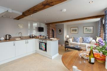 The spacious open plan living-room has kitchen and dining areas and beyond a really comfortable living area with wood burning stove.