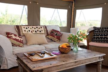 The sitting-area has a sofa and chair strewn with soft cushions.
