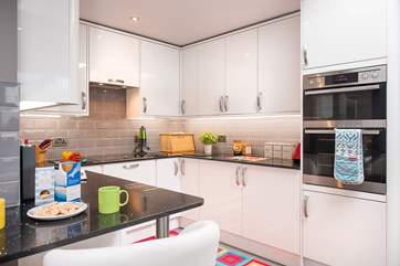 The contemporary kitchen has a little breakfast-bar, an ideal perch for breakfast or morning coffee, or to sit and keep the cook company.