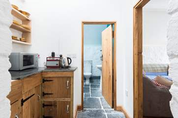 The kitchenette is next to one of the bathrooms and is opposite the snug, there is a step down to this part of the house.