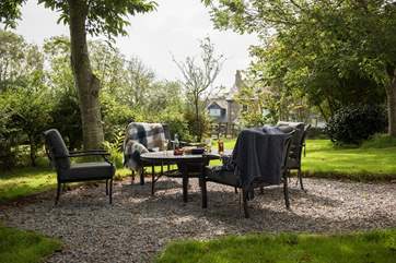 The private garden looks out over a meadow, with a fire-pit and comfortable, cushioned seating...