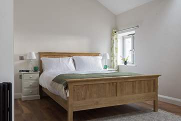 There is a lovely king-sized wooden bed.
