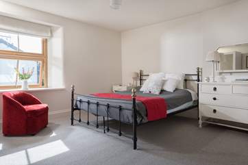 The master bedroom is furnished with an ornate metal king-size bed.