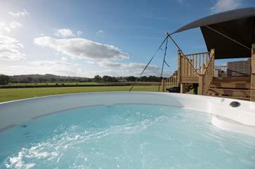 The bubbling electric hot tub sits proud on the deck just to the side of the tent.