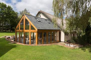 Another view of the oak-framed garden/dining-room. Take care with small children as there is a drop from the edge of the lawn to the path around this part of the building.