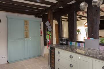Bespoke fitted cupboards house the microwave as well as plenty of storage space.