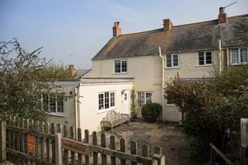 The cottage is accessed via the rear patio, with the two private parking spaces in the foreground.