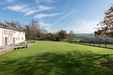 The open plan kitchen/dining/living space opens onto a wide terrace with the lawns sweeping around the front of the farmhouse.