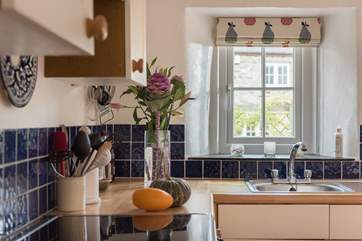 The kitchen overlooks the front garden terrace with the owners' home just visible. The trellis covered with climbing plants provides a privacy screen.