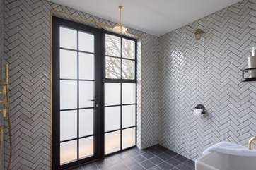 The wet-room has floor to ceiling herringbone tiles and a glass shower screen.