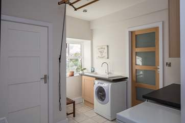 The spacious utility-room is neatly connected to the kitchen. Perfect for storage or a spot of food preparation.