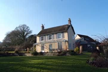 The lawned gardens spread out in front of the house, around the side there are further gardens, an outside pizza oven and a fenced pond.