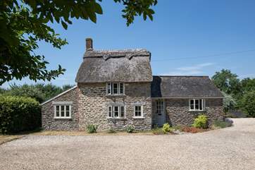 This listed, thatched cottage has a private south-facing garden behind the cottage, the owner's house is to the right.