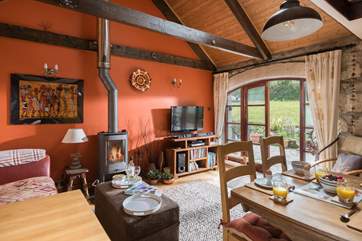The warm and sunny open plan kitchen, dining and sitting area, with French doors leading out onto the patio (the wood-burner is ornamental).