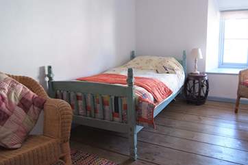The comfortable single bedroom with its beautiful wooden flooring.