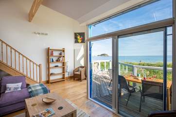 French windows lead out from the living area to the balcony and, across the railway line is the sea.