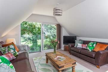 The open plan sitting-room is richly styled in greens and browns to complement the outside.