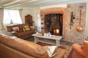 The inglenook fireplace with wood-burning stove is at the heart of this welcoming homely cottage.