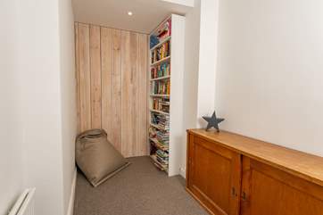 Even the first floor landing doubles up as functional space. A full bookshelf and cupboard full of toys are there to enjoy.