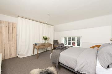 Hanging space is behind the linen screen. Tasteful grey bed linens and thick sheep fleeces from the special flock here add a touch of luxury.