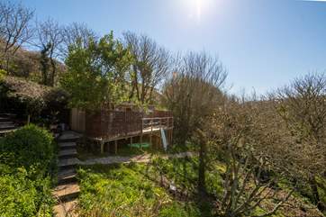 This idyllic retreat is sat high up in the trees with a peaceful stream trickling through below and the sea only a few yards away.
