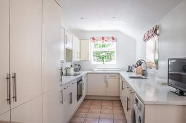The modern sleek kitchen is very well-equipped and has a television.