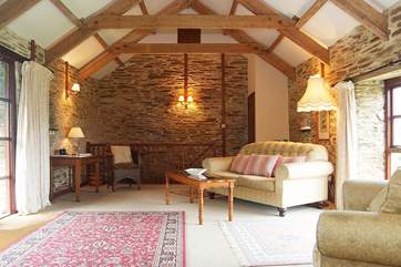 The spacious open plan living-room has a wonderful high apex ceiling showing the lovely old beams.